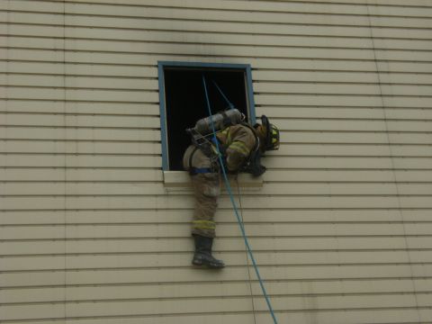 1992 Ford F-150 - Firefighter rappels down a building from an upper window using a rope and harness.