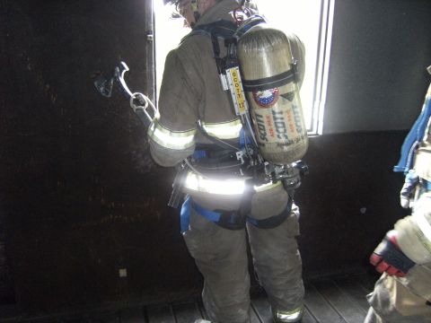 1992 Ford F-150 - A firefighter prepares to breach a wall with an axe while wearing a self-contained breathing apparatus.