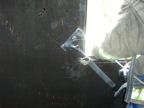 1992 Ford F-150 - A firefighter is seen using an axe, possibly for rescue or entry, against a dark, textured surface with a bright light source in the backgr…