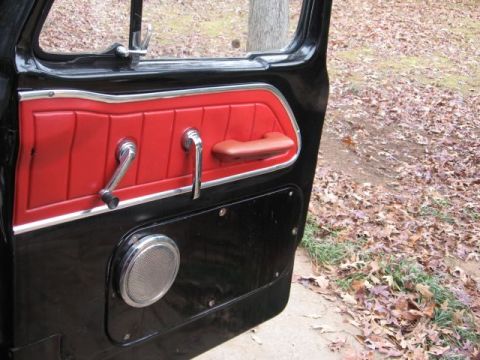 1966 Ford F-100 - The interior door panel of a vintage truck features red vinyl inserts and a chrome speaker grille.