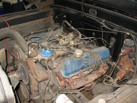 1966 Ford F-100 - Engine bay of a vintage Ford pickup with the air cleaner removed, showing a well-used Ford V8 with faded blue valve covers, a two-barrel ca…