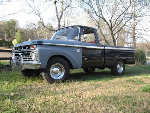 1966 Ford F-100 - Three-quarter front view of a black mid-1960s Ford F-100 shortbed styleside pickup wearing gray primer on the hood and front fender, with c…