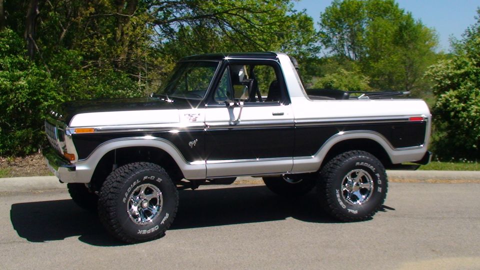 1979 Ford Bronco, black and white, two-door, chrome wheels, off-road tires, parked outdoors.