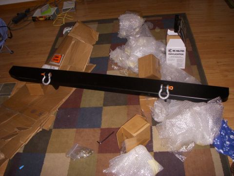 1989 Ford Bronco - A black aftermarket front bumper with two D-ring shackle mounts is laid out on a colorful rug next to its packaging materials and a box for…