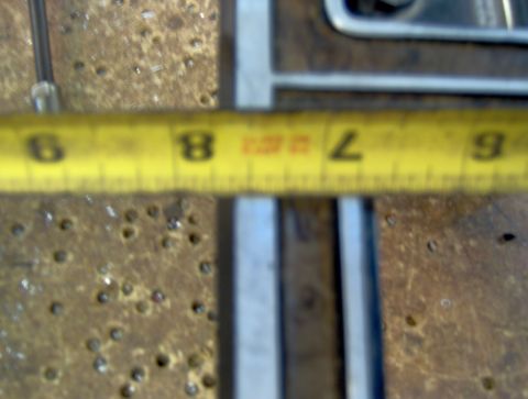 1978 Ford Bronco - A yellow measuring tape is positioned over a rusty metal surface. The tape shows markings for inches, with the numbers 6, 7, 8, and 9 clear…