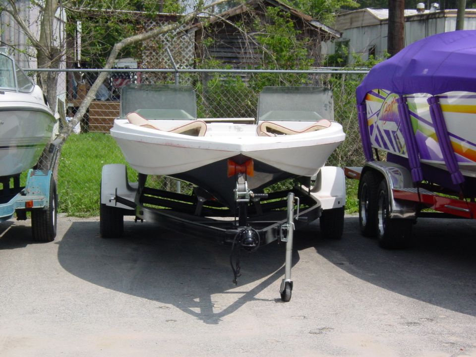 Two boats on trailers, one white, one covered in a purple tarp.
