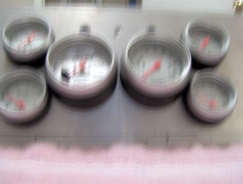 1978 Ford Bronco - A close-up, motion-blurred photo shows a bank of six gauges, likely in a vehicle dashboard. The gauges have white faces, red needles, and s…
