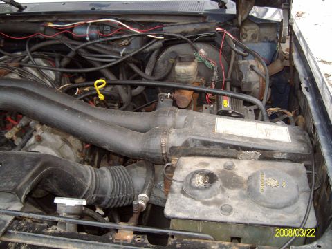 1988 Ford Bronco - Engine compartment showing intake snorkel tube, air box, wiring harness and a Motorcraft battery under an open hood.