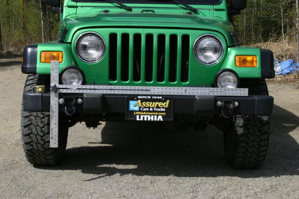 Green Jeep Wrangler front bumper with a measuring tool attached