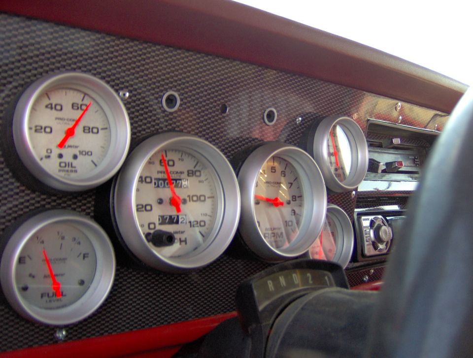 Dashboard with aftermarket gauges including oil pressure, fuel level, tachometer, and speedometer. Radio and gear selector visible