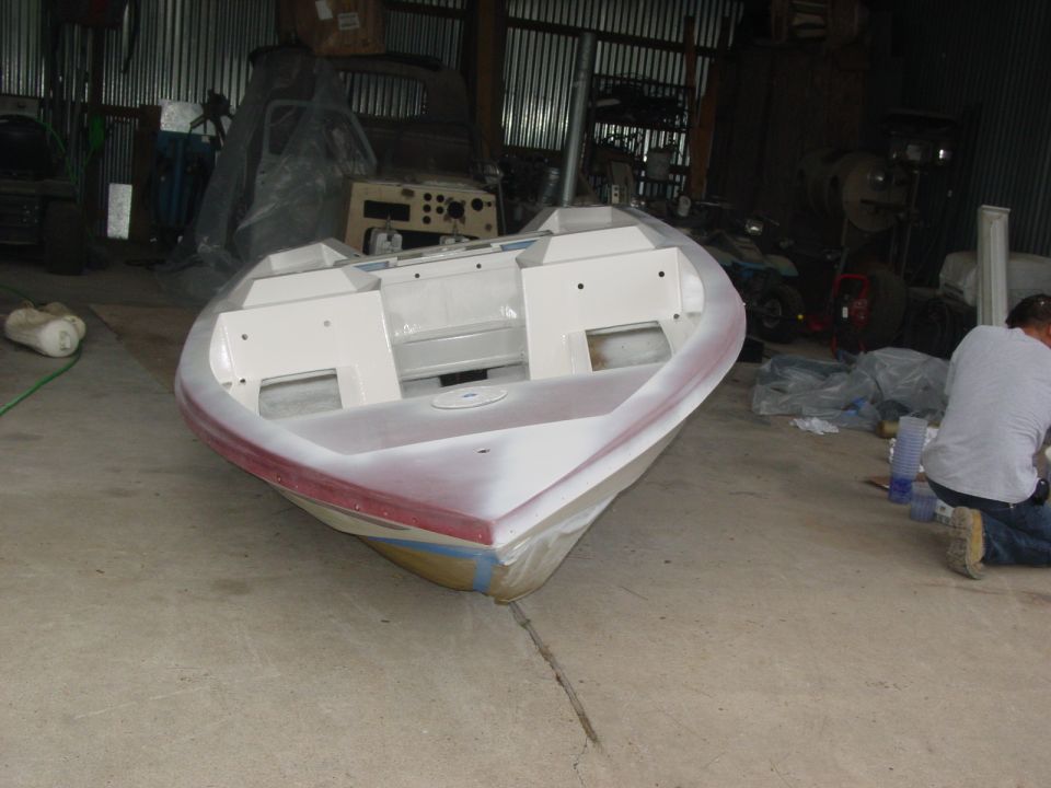 Bow of small fiberglass boat in primer during restoration in a workshop