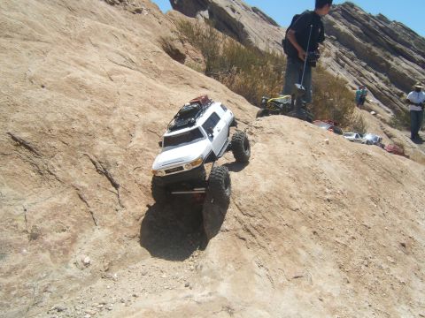 1988 Ford Bronco - A remote control rock crawler navigates a steep, rocky incline under a clear blue sky.