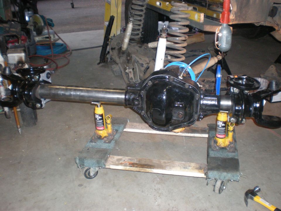 Black Ford Bronco rear axle assembly on jacks and dolly in garage.