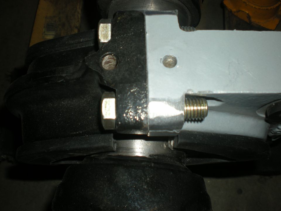 Close-up of vehicle suspension part with black bushing and gray metal bracket.