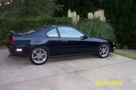 2001 Ford Crown Victoria - Side view of a dark green coupe with custom wheels parked outdoors.