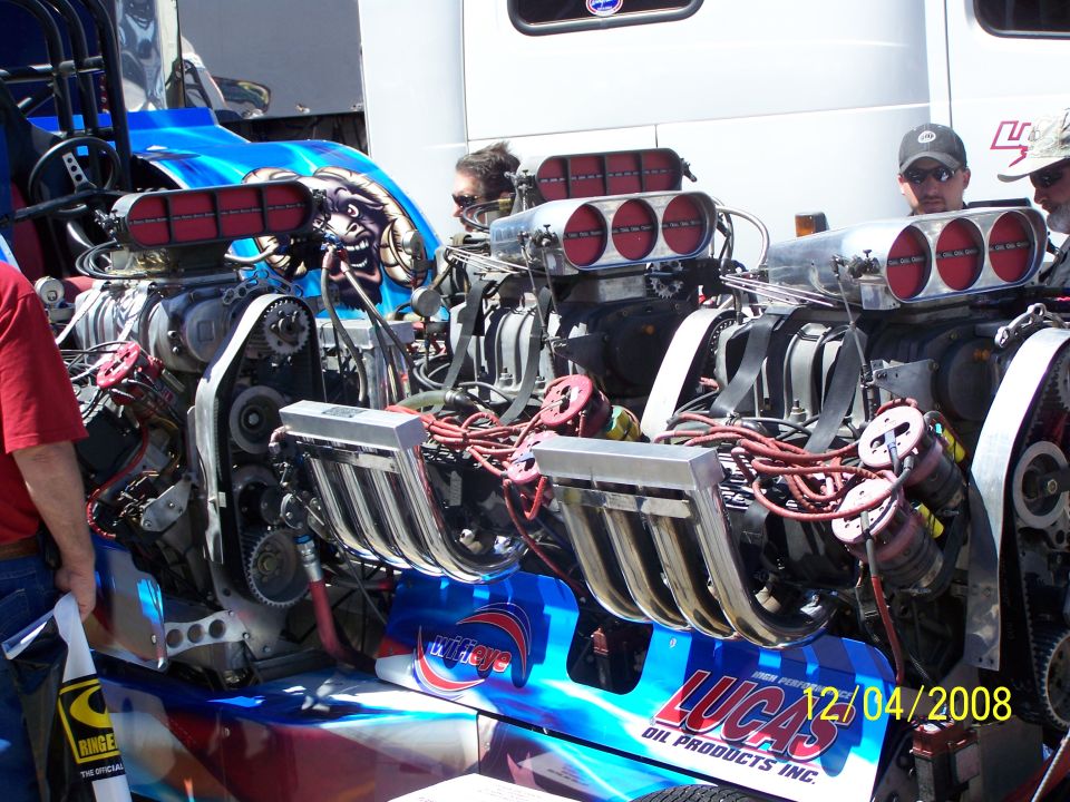 Dual supercharged engine with chrome headers and red air intakes. Graphics on the body include 'Lucas Oil Products'