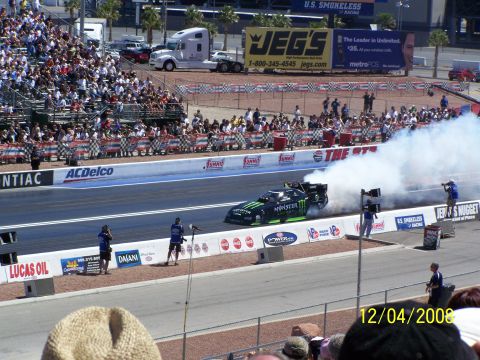 1973 Ford Mustang - A drag car performs a burnout at a race track, generating a large cloud of smoke.
