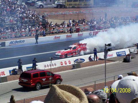 1973 Ford Mustang - A dragster creates a large cloud of smoke during a burnout at a race event.