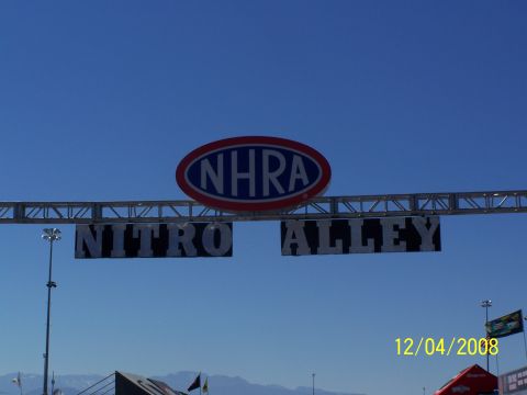 1973 Ford Mustang - A sign reads NHRA Nitro Alley against a clear blue sky.