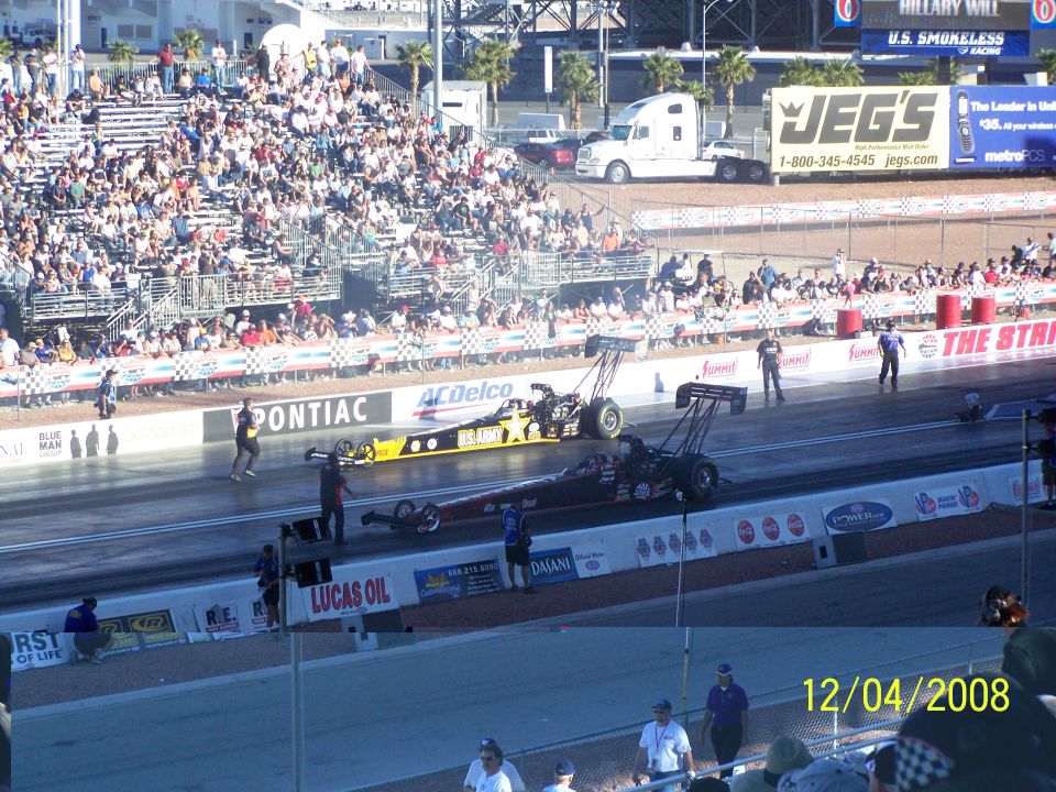 Two drag racing cars on a track with spectators in the stands