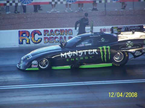 1973 Ford Mustang - A drag racing car with Monster Energy branding speeds down the track.