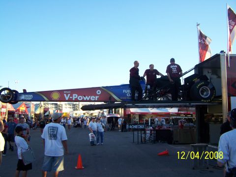 1973 Ford Mustang - A dragster is prepared for transport at an outdoor event, with spectators in the background.