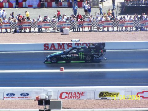1973 Ford Mustang - A drag racer with Monster Energy branding speeds down the track during a race event.