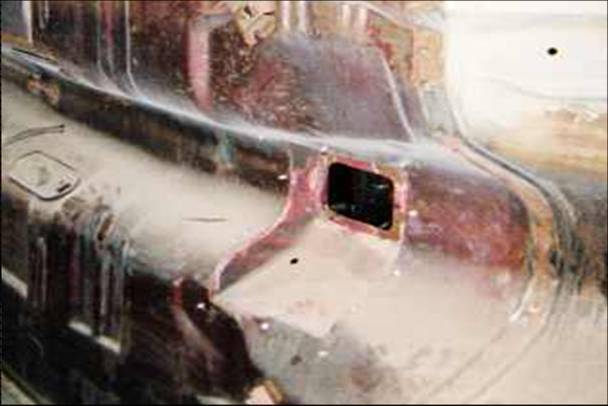 Rusty vehicle quarter panel with cut hole and surface rust