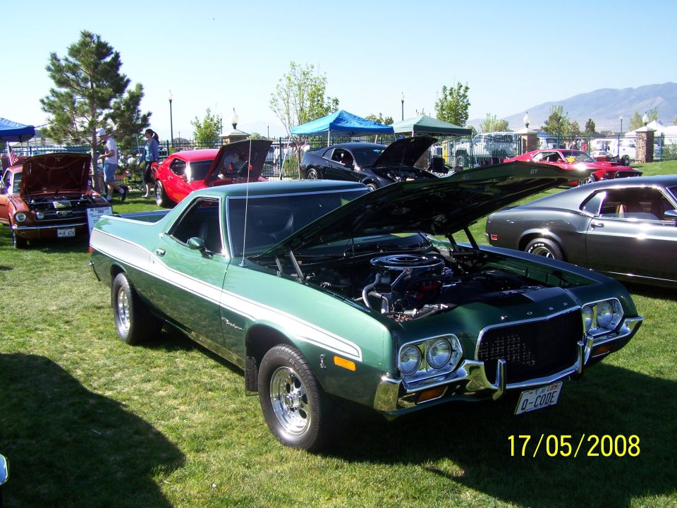 Green 1972 Ford Ranchero with white side stripe, hood open, parked on grass