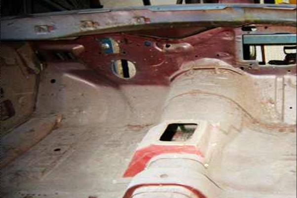 Stripped interior firewall and floor of a bare vehicle shell