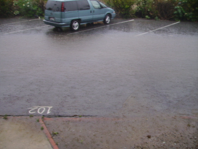 Teal minivan parked in a flooded parking lot.