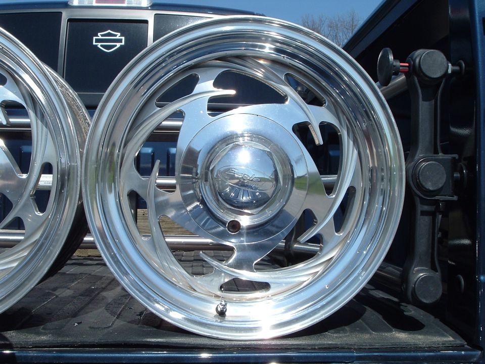 Polished Eagle Alloys swirl-spoke wheel with logo center cap in a pickup bed
