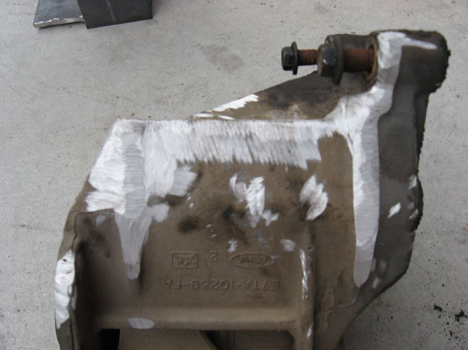 Ford-stamped bracket part number E7TA-10229-FA with rusty stud, on concrete