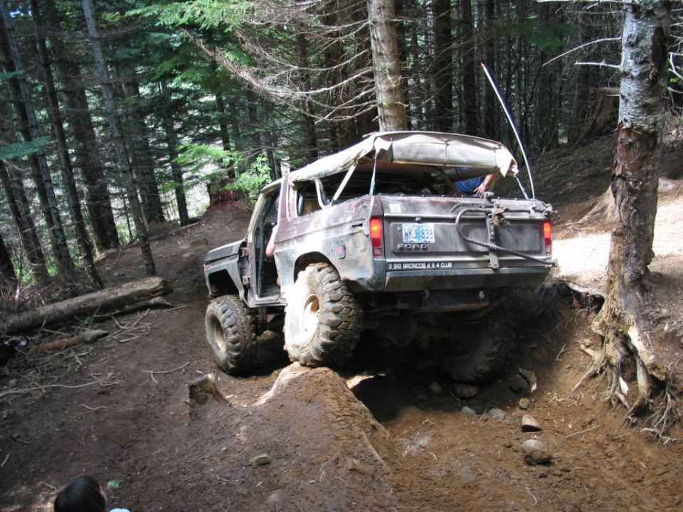 Dark brown Ford Bronco off-roading on a dirt trail with a soft top
