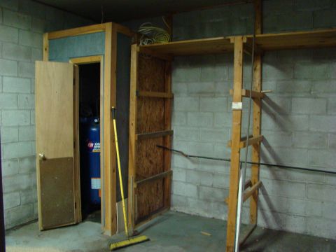 1948 Jeep Wrangler - A blue propane tank is visible inside a small room with a wooden door slightly ajar. A yellow broom leans against the wall next to the door.