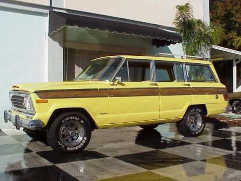 1984 Ford Bronco - A yellow Jeep Grand Wagoneer with wood paneling is parked on a checkered black and white tiled surface. The vehicle is viewed from the side…
