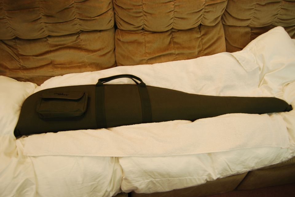 Dark green rifle case on a bed.