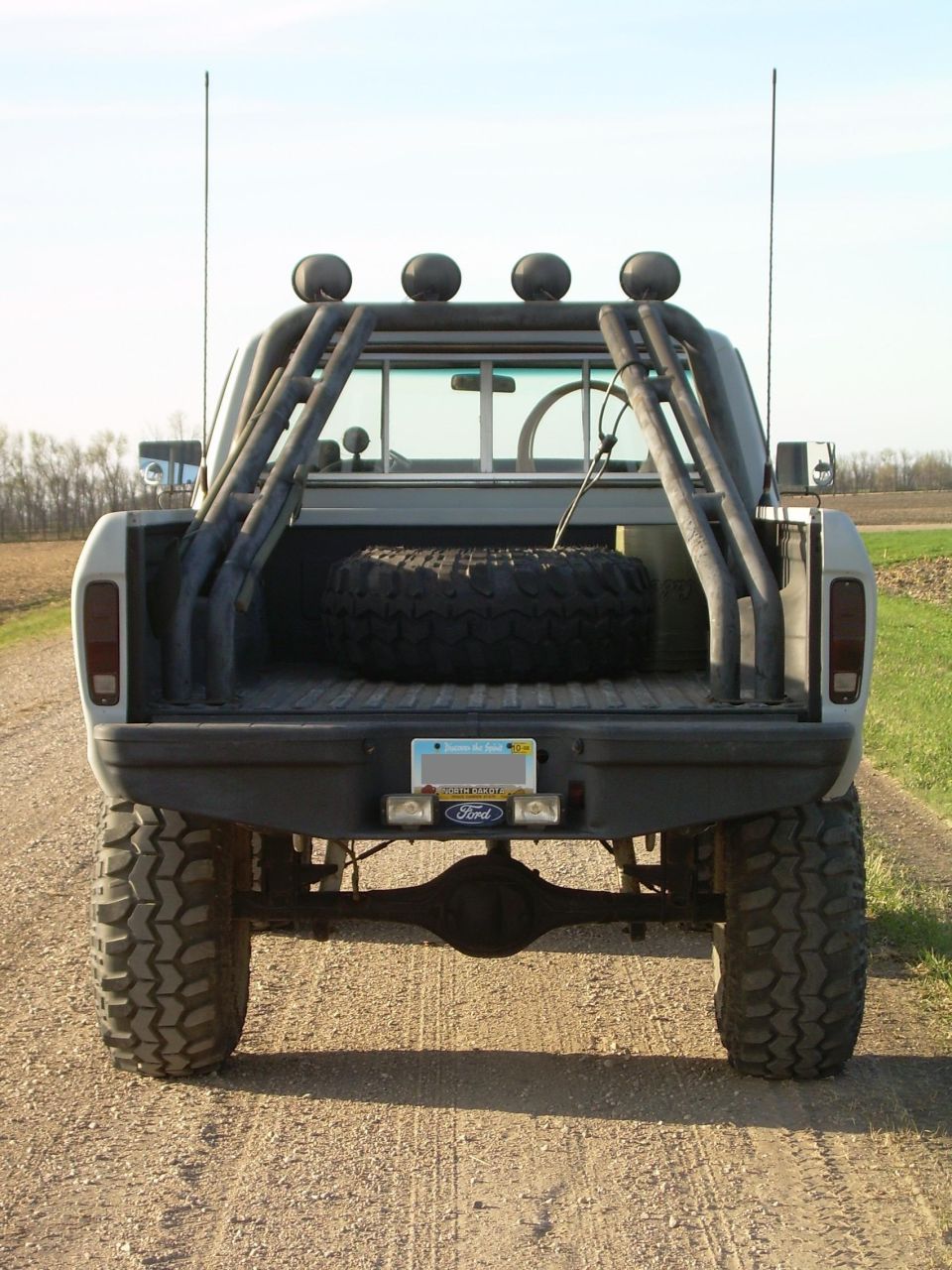 Rear view of a lifted 1978 Ford F-150 pickup truck with off-road tires and a roll cage.