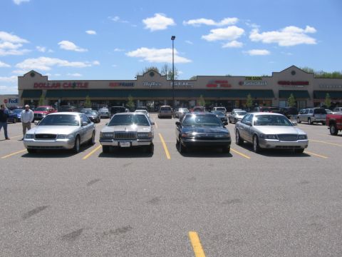 1988 Mercury Grand Marquis - A silver 1988 Mercury Grand Marquis is parked in a lot in front of a strip mall. The car is viewed from the front 3/4 angle.