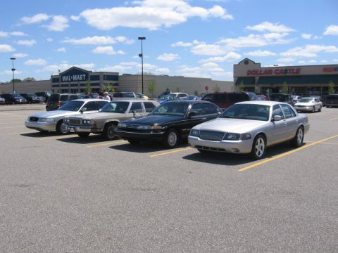 1988 Mercury Grand Marquis - A silver 1988 Mercury Grand Marquis is parked in a lot in front of a Walmart and a Dollar Castle store.