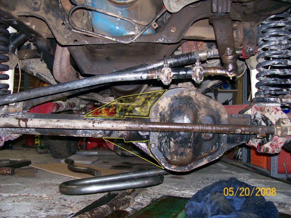 Underside view of a solid rear axle and coil springs with annotations