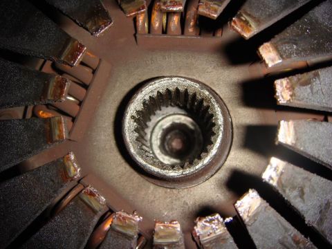 1975 Chevrolet Corvette - Close-up view of a worn clutch disc with a splined hub in the center. The friction material is visibly degraded and appears to be separatin…