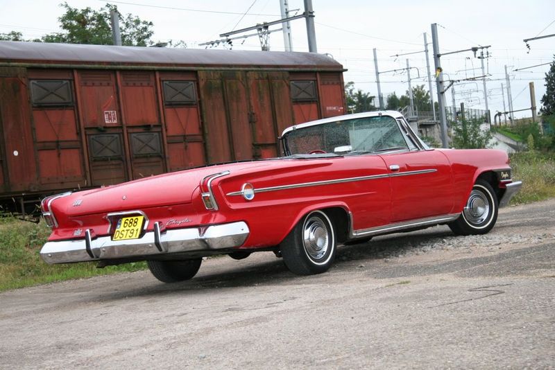 Red convertible with fins parked near a train car