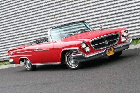 1991 Ford Crown Victoria - A classic red convertible is parked on a paved surface with a grey wall in the background.