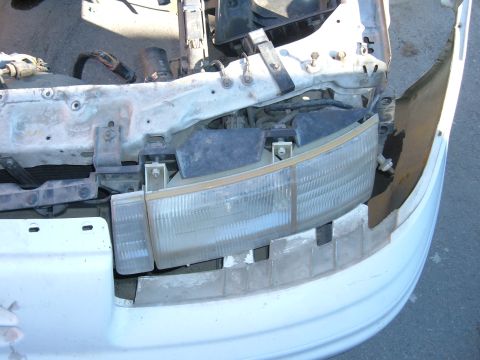 1995 Ford Taurus - The front end of a car is shown with the headlight assembly removed, revealing the underlying structure and wiring.