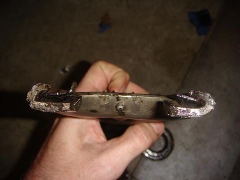 1975 Chevrolet Corvette - A close-up view of a damaged metal component being held by a hand.