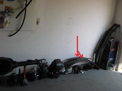 1991 Ford Bronco - Various vehicle parts are organized against a wall in a garage setting.