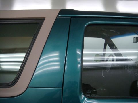 1996 Ford Bronco - Close-up of the side of a teal SUV, highlighting the door frame and window area.