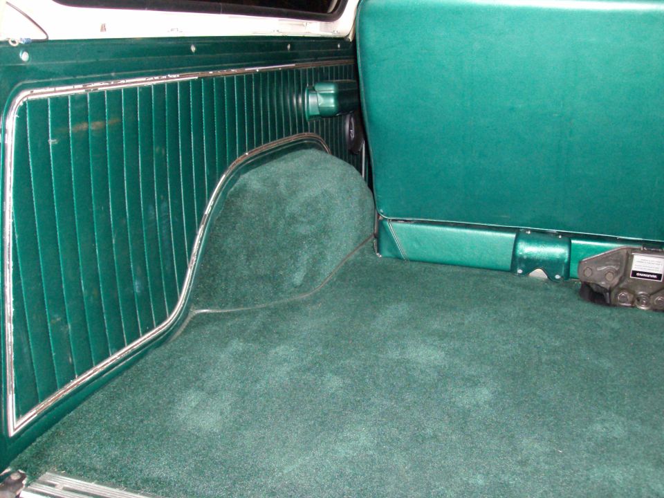 Green carpeted interior cargo area with ribbed paneling and a seat