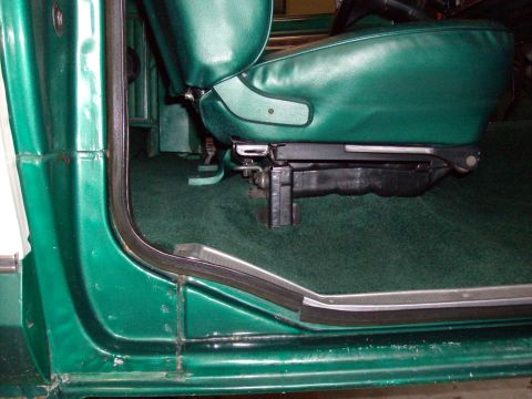 1978 Ford Bronco - Interior view of a green vehicle showing the seat base and carpet.